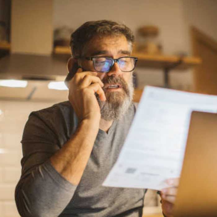 A seated man wearing glasses reviewing a document
