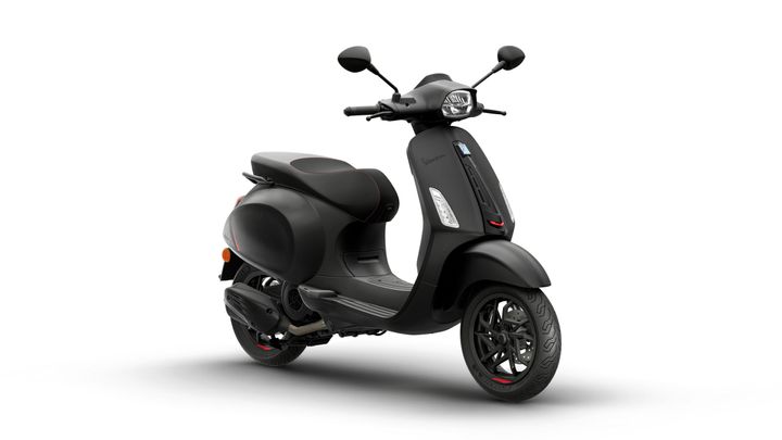A sleek black scooter with a modern design, featuring a curved frame, a comfortable seat with red accents, and stylish alloy wheels. The scooter stands on a white background, highlighting its minimalist aesthetic.