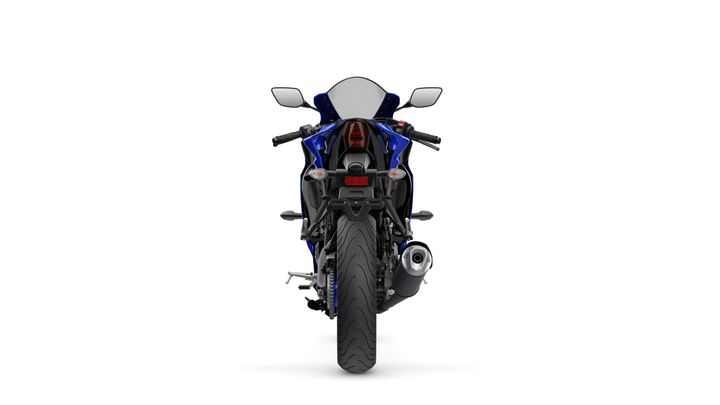 A blue sport motorcycle viewed from the rear, showcasing the exhaust pipe, tail light, and sleek design features against a white background.