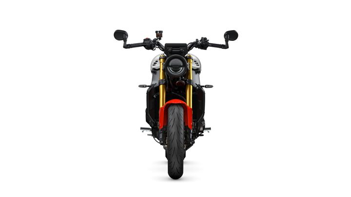 A front view of a modern motorcycle featuring a black and gold frame, distinctive round headlight, and red accent on the front fender, set against a white background.