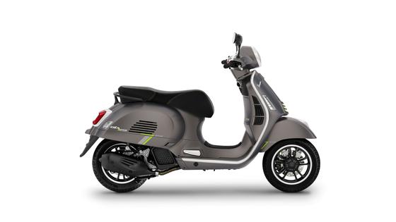 A side view of a gray Vespa scooter featuring sleek design elements, green accents, and modern styling.