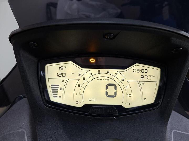 Digital motorcycle dashboard displaying speed (0 mph), distance (120 miles and total 27 miles), engine RPM, fuel level (F to E), temperature (19°C), and time (09:03).