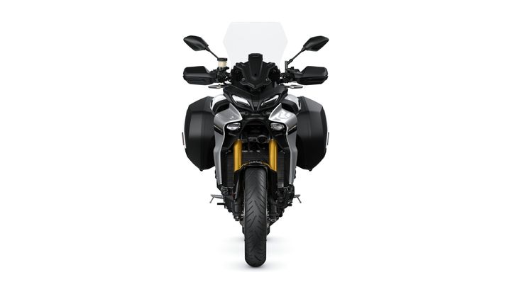 Front view of a modern motorcycle with a black and silver design, featuring side panniers, a tall windshield, and distinctive dual headlights.