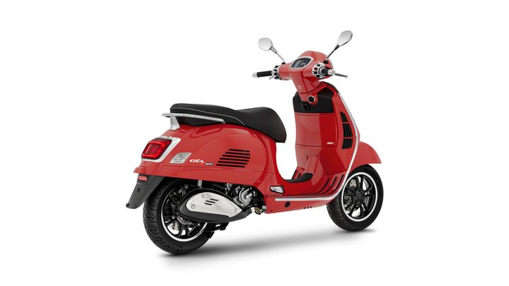 A red scooter with a sleek design, featuring a comfortable seat and a black rear fender, angled to show its side and rear view.