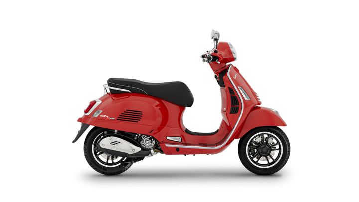 A sleek red scooter with a black seat, featuring chrome accents and a stylish design, positioned against a white background.