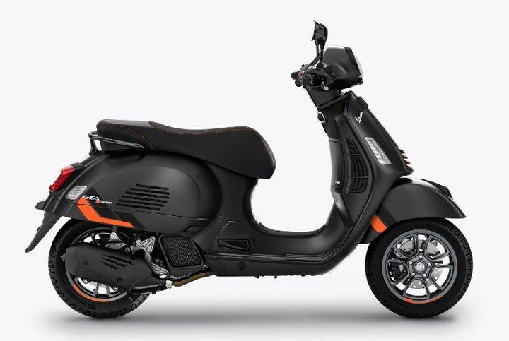 A black modern Vespa scooter with orange accents on a white background.