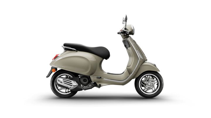 A side view of a sleek, beige scooter with a black seat, featuring chrome accents and stylish wheels, set against a white background.