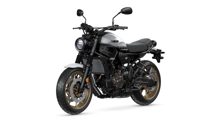 Yamaha XSR motorcycle with a modern retro design, featuring a silver and black color scheme, a round headlight, and gold alloy wheels.