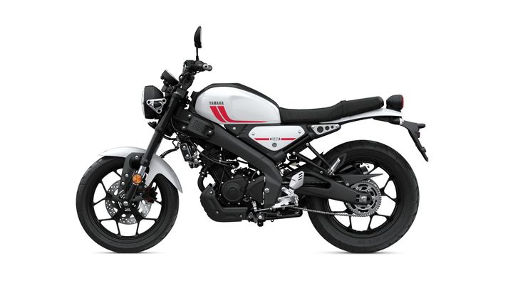 A sleek white and black Yamaha motorcycle with red accents, viewed from the side, showcasing its modern design and circular headlight.
