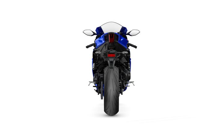 A blue sports motorcycle viewed from the rear, showcasing its sleek design, prominent rear tire, and dual exhausts.