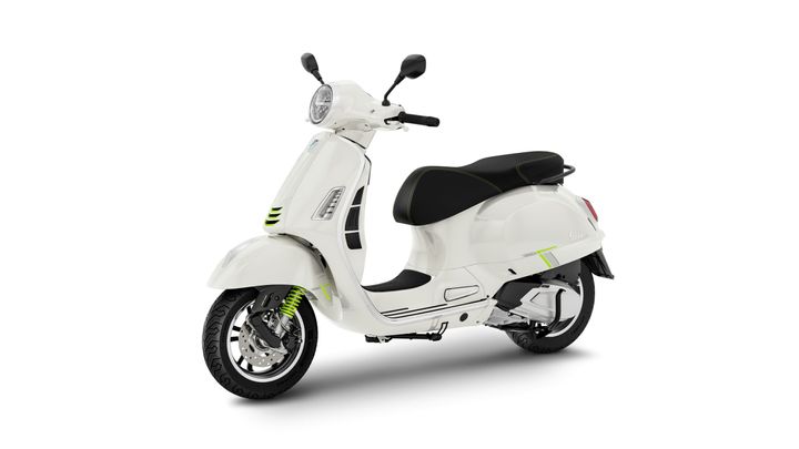A sleek white scooter with green accents, featuring a round headlight, a black seat, and stylish curves, positioned at a slight angle.
