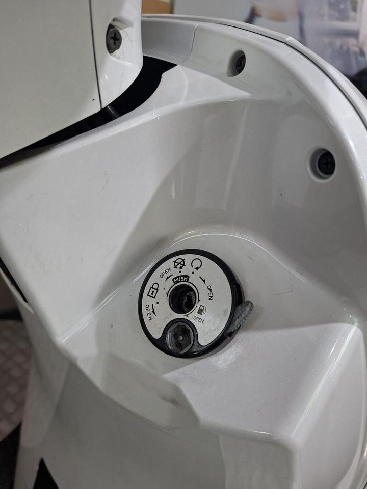 Close-up of a white control panel featuring a circular interface with labeled openings and push instructions, mounted on a surface with visible screws and a slight sheen.