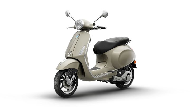 A beige scooter with a retro design, featuring a round headlight, chrome mirrors, and a plush black seat, positioned at a slight angle against a white background.