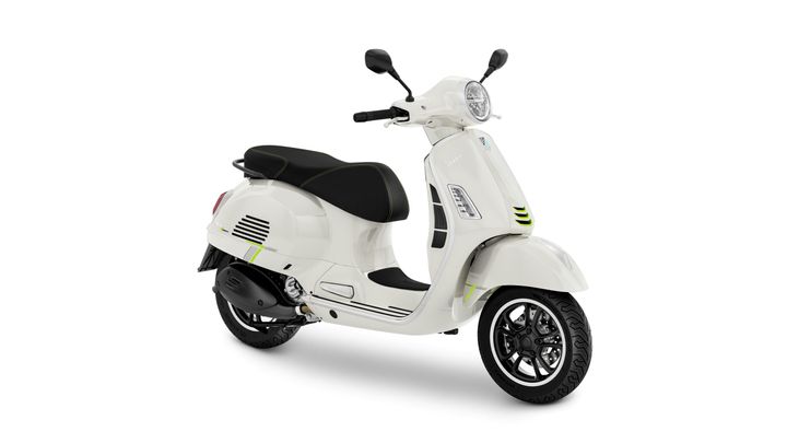 A white scooter with a sleek design, featuring a black seat with green stitching, a rounded headlight, and modern wheels, positioned at a slight angle.