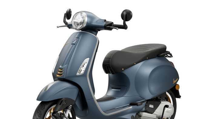 A blue vintage-style scooter with a sleek design, featuring a rounded front, silver accents, and a black seat with horizontal stripes, displayed at a slight angle.