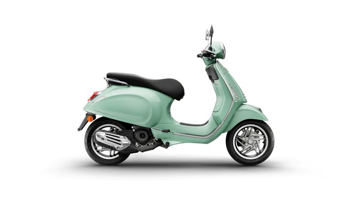 A mint green scooter is shown from the side, featuring a black seat and chrome accents. The background is plain white, emphasizing the scooter's sleek design.
