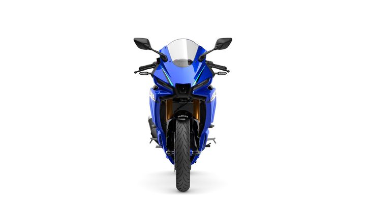 A blue motorcycle viewed head-on, showcasing its sleek design, prominent headlights, and a distinctive front fairing. The vehicle features black mirrors and a textured tire in the foreground.