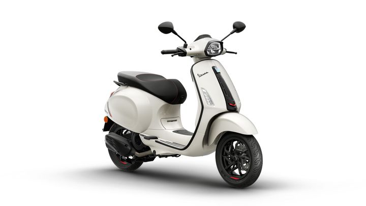 A modern beige scooter with a sleek design, featuring a black seat and red stitching, positioned at an angle to showcase its profile and wheel details.