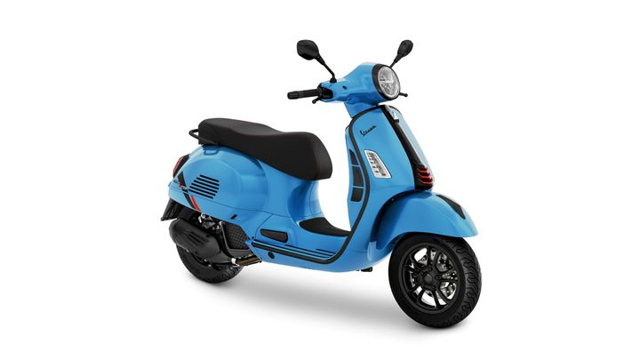 A vibrant blue Vespa scooter with a sleek design, featuring a comfortable black seat and modern styling elements, is positioned at a slight angle against a white background.