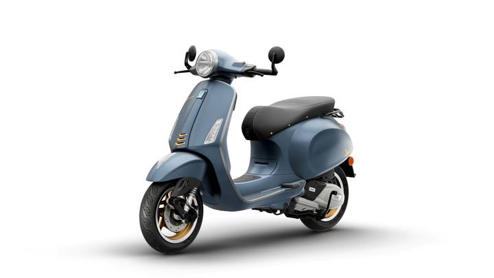 A vintage-style blue scooter with a black seat, featuring chrome accents and a round headlight, displayed against a white background.