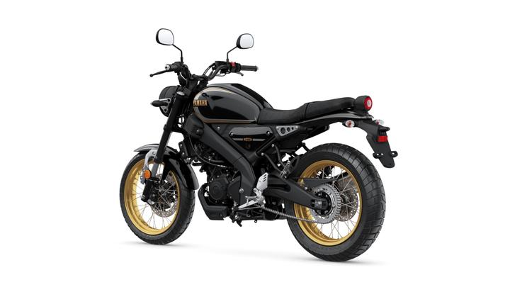 A black Yamaha motorcycle with gold rims, viewed from a slight rear angle, showcasing its sleek design and modern features.