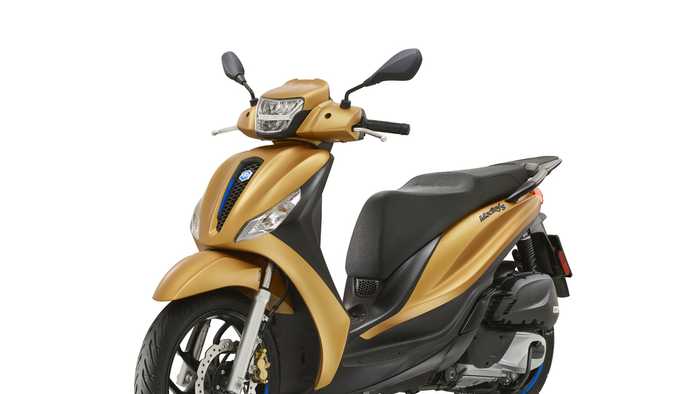 A golden scooter with a sleek design, featuring a comfortable seat, front headlight, and modern wheels, displayed at an angle to highlight its profile.