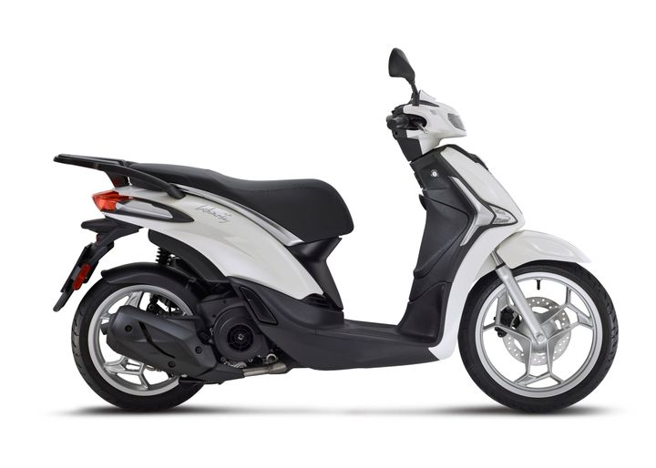 Piaggio Liberty 125 Euro 5+ A sleek, white scooter with a black seat, showcasing a modern design with a small windscreen, side mirrors, and a stylish wheel rim.