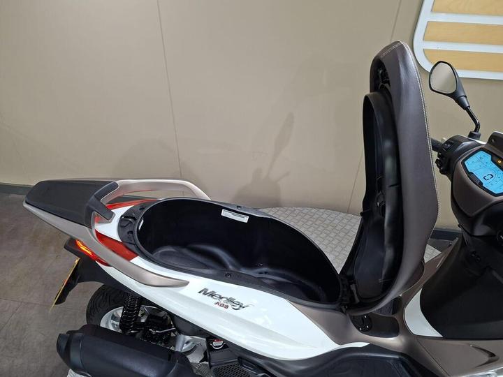 A close-up view of the open storage compartment of a white and brown scooter, highlighting its design and interior space.