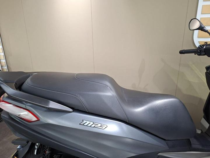 Close-up view of the seat and rear section of a gray MP3 scooter, showcasing its sleek design and texture against a neutral background.