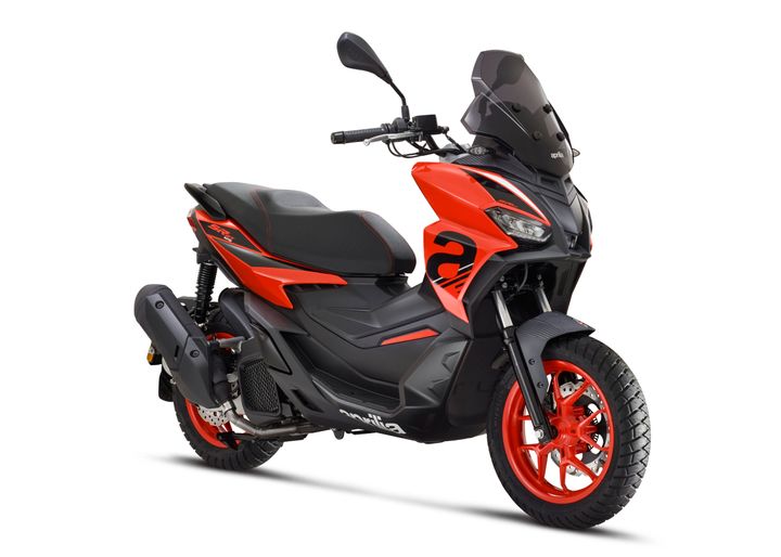 A sporty orange and black scooter with a sleek design, featuring a tinted windshield, prominent headlights, and unique wheel rims.