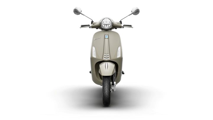 A front view of a beige scooter with a round headlight, chrome mirrors, and modern design elements, set against a white background.