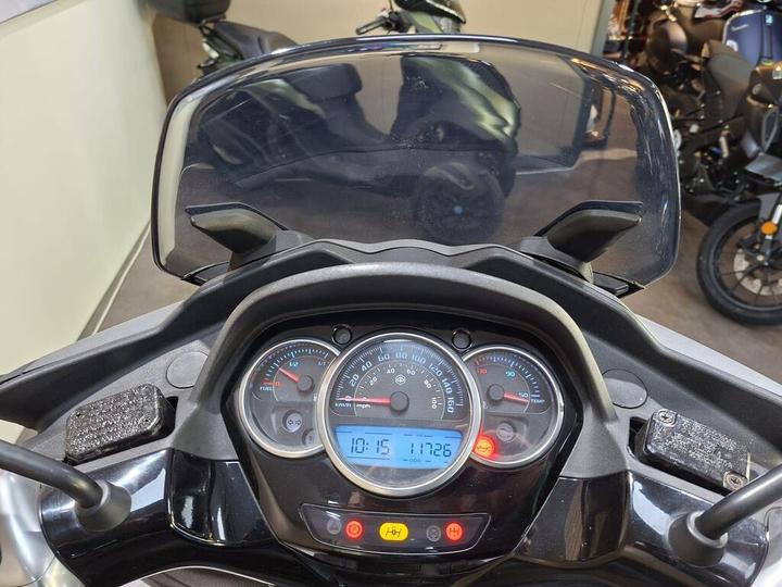 Dashboard view of a motorcycle displaying the speedometer, fuel gauge, temperature gauge, and various indicator lights.