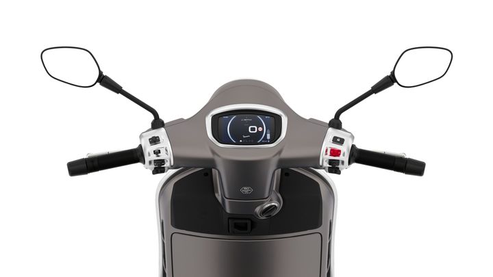 The handlebars of a modern scooter, featuring a digital dashboard display and control switches on either side, with mirrors extending outward.