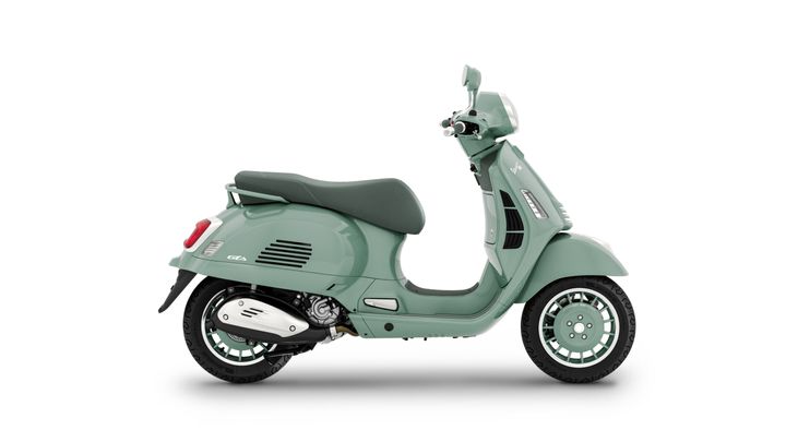 A mint green vintage-style scooter is shown in profile, displaying its sleek design, round headlight, and comfortable seat. The scooter features chrome accents and distinctively patterned wheels.