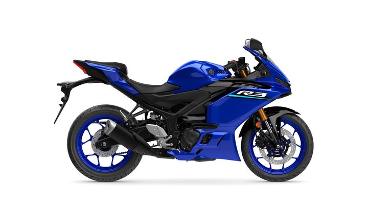 A side view of a blue Yamaha R3 motorcycle, featuring a sporty design with a black and blue color scheme, sleek bodywork, and lightweight wheels.