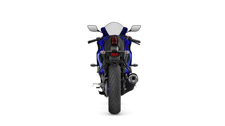 A blue sport motorcycle viewed from the rear, showcasing its sleek design, rear tire, and exhaust pipe against a white background.