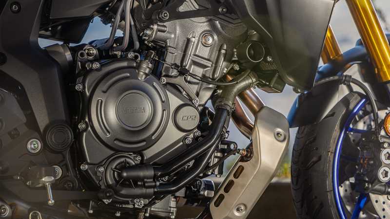Close-up view of a Yamaha motorcycle engine, showcasing intricate metallic components, including the engine casing, pipes, and connecting parts, with a blurred background.