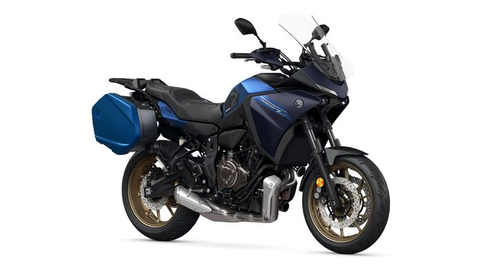 A blue and black Yamaha Tracer 9 GT motorcycle with a sleek design, featuring a windshield, gold-painted wheels, and side panniers, displayed against a white background.