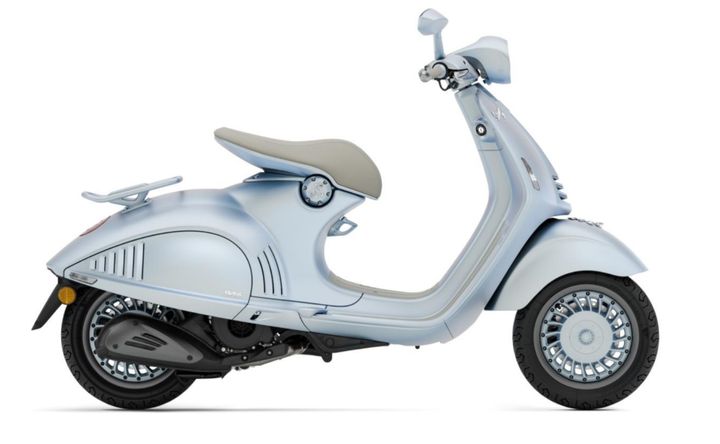 Vespa 946 Snake A light blue vintage-style scooter with a rounded design, featuring a beige seat and detailed wheel rims, positioned on a white background.