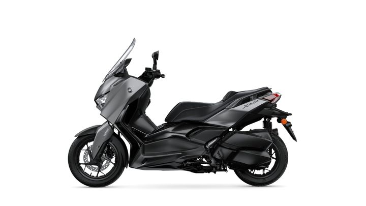 A sleek, modern gray scooter with a streamlined design, featuring a tall windshield, comfortable seat, and sporty wheels, positioned against a plain white background.