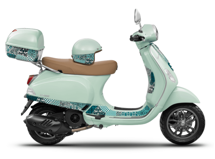 A mint green scooter with patterned detailing, a matching helmet, and a tan seat, displayed in profile view against a white background.