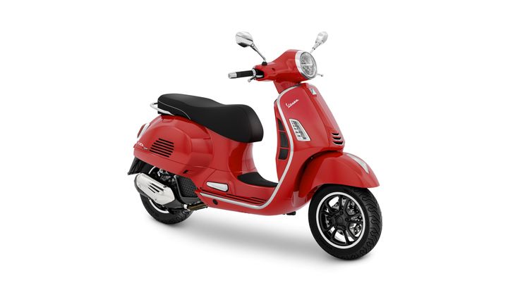 A red scooter with a sleek design, featuring a black seat, chrome details, and a front light, positioned on a white background.