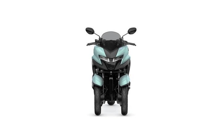 A front view of a light blue three-wheeled motorcycle, featuring a modern design with a sleek body, twin headlights, and a windscreen.