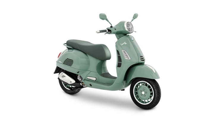 Vespa GTS 80th 310 A mint green Vespa scooter, featuring a comfortable seat, chrome accents, and stylish wheels, positioned at an angle to showcase its design.