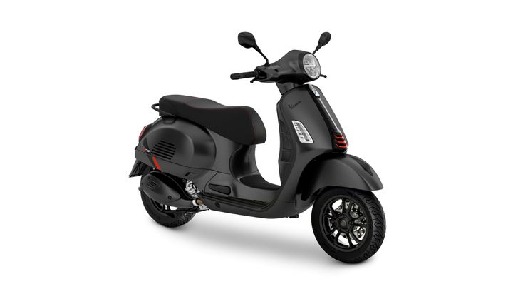 A sleek black scooter with red accents, featuring a round headlight, a comfortable seat, and stylish alloy wheels, positioned slightly angled to showcase its design.