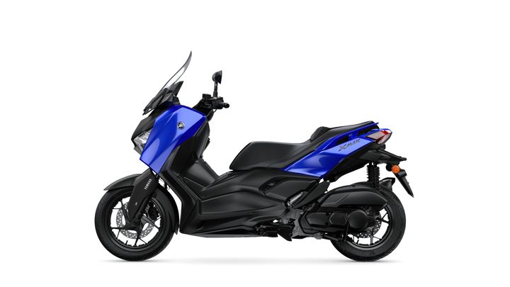 A blue Yamaha XMAX scooter shown from the side, featuring a sleek design, with a black seat and accents, and a transparent windscreen.