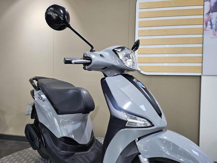 A sleek gray scooter with a black seat, featuring a rearview mirror and modern design elements, displayed against a neutral background.