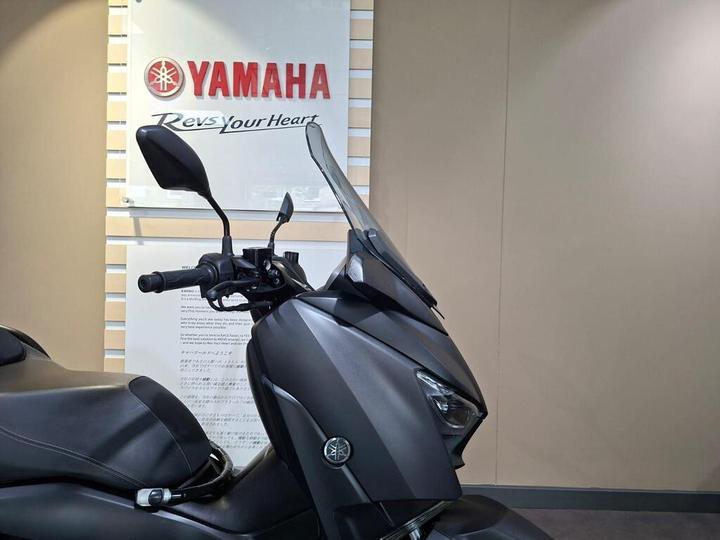 A close-up view of a Yamaha motorcycle showcasing the handlebars, windscreen, and the Yamaha logo on the wall in the background.