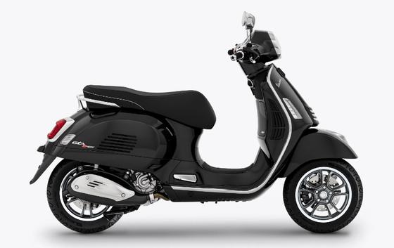 A side view of a black modern Vespa scooter against a white background.