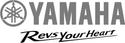 Logo of Yamaha featuring the brand name "YAMAHA" in bold red letters above the tagline "Rev's Your Heart" in a stylized black font, accompanied by a circular emblem with a triple tuning fork design in red.